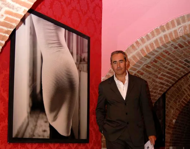 José Mº Díaz-Maroto junto a una fotografía de Isabel Muñoz . La polémica e innovadora manipulación nos lleva a las grandes aportaciones de Joseph Renau, Juan Manuel Castro Prieto, Kim Joon, Bill Brand, Jo Brunenberg, André Kerész, Man Ray, Philippe Halsman y Manuel Sonseca que con un nuevo aporte fotográfico, se mueve en unos espacios hasta ahora inexplorados “el encuentro con el cuerpo y su desnudo”, lo aborda evitando el encuentro real, piel a piel, y lo sustituye por una cita cibernética donde manipula lo explícito, se apropia de lo vulgar y subvierte el concepto de pornografía para descansar finalmente en la forma. Internet ha sido la fuente de dicha imagen pornográfica que tratada con una sutil alquimia digital, sometiéndola a una metamorfosis - esencial- surgen nuevas fotografías arropadas por un halo de elegante erotismo, que nos acerca a los clásicos del género. El erotismo, la voluptuosidad, la provocación, la pasión y la sensualidad tienen los mejores representantes posibles para esta muestra. Observe con detenimiento las obras maestras de Ralph Gibson, Isabel Muñoz, Günter Blue, Toni Catany, Lucien Clergue, Claude Fauville, Miguel Oriola, Susan Míeselas, Elien Von Unwerth, Alberto García-Alix y de Helmut Newton.